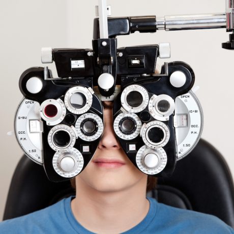 Boy sitting while undergoing an eye test with phoropter in the clinic